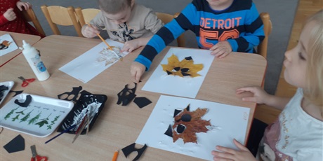 Powiększ grafikę: Dzieci wykonują pracę plastyczną z wykorzystaniem liści.