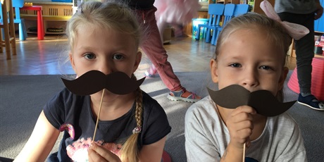 Powiększ grafikę: Dziewczynki z przyłożonymi do twarzy wąsami.