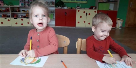 Powiększ grafikę: Dwoje dzieci siedzi przy stoliku i koloruje dynię.