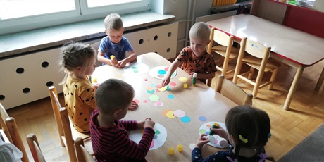 Powiększ grafikę: Dzieci ozdabiają koła kolorowymi kropkami.