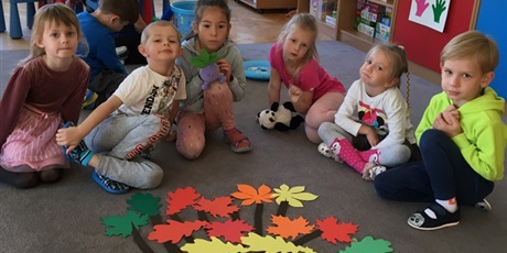 Powiększ grafikę: Dzieci prezentują drzewo ozdobione wyciętymi liśćmi.