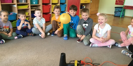 Powiększ grafikę: Dzieci obserwują jak unosi się balon nad włączoną suszarką.